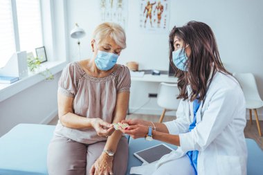 Kadın doktor, hastanedeki kıdemli hastasına ilaç veriyor.