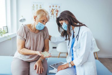 Kadın doktor, hastanedeki kıdemli hastasına ilaç veriyor.
