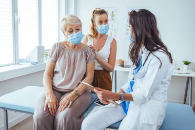 Kadın doktordan kıdemli kadın ve yetişkin kızı. Profesyonel gülümseyen doktor, kıdemli bir hasta ve kızıyla hastanede buluşuyor.