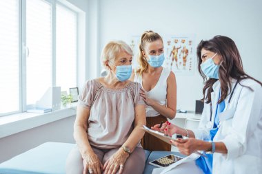 Son sınıf öğrencisi bir kadın ve kızının doktor randevusu var. Profesyonel gülümseyen doktor, kıdemli bir hasta ve kızıyla hastanede buluşuyor.