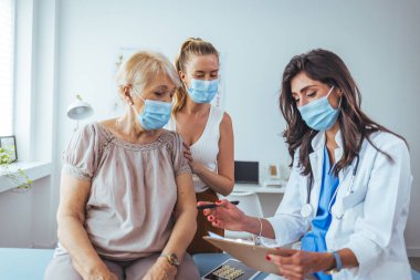 Kadın doktordan kıdemli kadın ve yetişkin kızı. Profesyonel gülümseyen doktor, kıdemli bir hasta ve kızıyla hastanede buluşuyor.