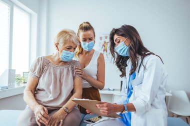 Kadın doktordan kıdemli kadın ve yetişkin kızı. Profesyonel gülümseyen doktor, kıdemli bir hasta ve kızıyla hastanede buluşuyor.