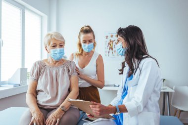 Kızın check-up randevusunda annesiyle oturuyor. Profesyonel gülümseyen doktor, kıdemli bir hasta ve kızıyla hastanede buluşuyor.