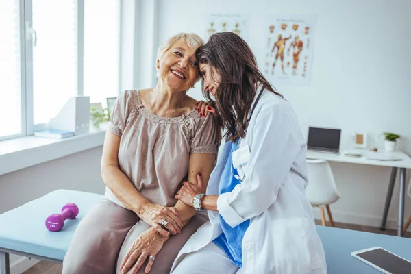 Neşeli ve arkadaş canlısı gülümseyen kadın bir doktor ve klinikteki kıdemli bir hastanın portresi.