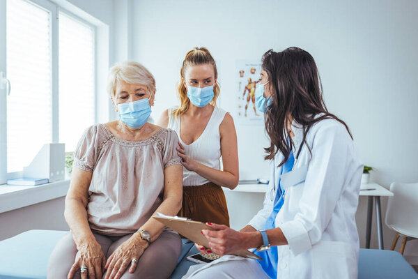 Дочь сидит с матерью на приеме у врача. Профессиональный улыбающийся врач встреча со старшим пациентом и ее дочерью в больнице, концепция медицинского обслуживания