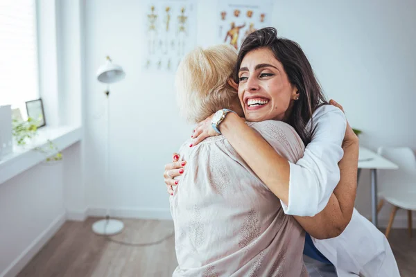 Portrait Cheerful Female Doctor Hugging Her Senior Patient Clinic — Stock Photo, Image