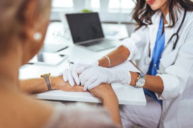 Doktor ve hasta klinikte bir şey tartışıyorlar, sadece ellerini masaya koy. Tıp ve en iyi hizmet kavramı. Doktor, klinikteki masada oturan hasta kadına güvence veriyor.