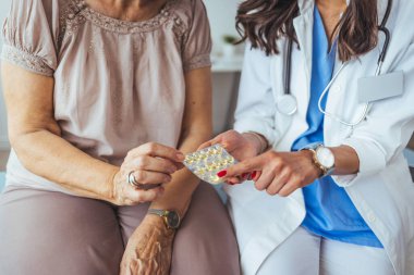Doktor kıdemli hastaya ilaç yazar. Kadın doktor klinikteki yaşlı kadın hastaya ilaç şişesi veriyor. Sağlık, tıbbi tedavi ve sigorta kavramı.