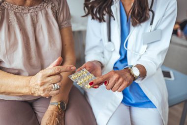 Doktor, kadın hastaya haplar hakkında danışmanlık yapıyor ve resepsiyonda oturan sağlık tedavisini engelliyor. Tıp ve sağlık hizmetleri kavramı. Doktor, ofisteki bir hastaya reçete yazıyor. 