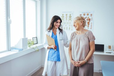 Gülümseyen genç bayan hemşire, yaşlı yaşlı büyükannenin tıbbi kontrol ziyaretinde rehabilitasyona yardım etmesine yardımcı oluyor, yaşlı insanlar sağlık hizmetleri konsepti