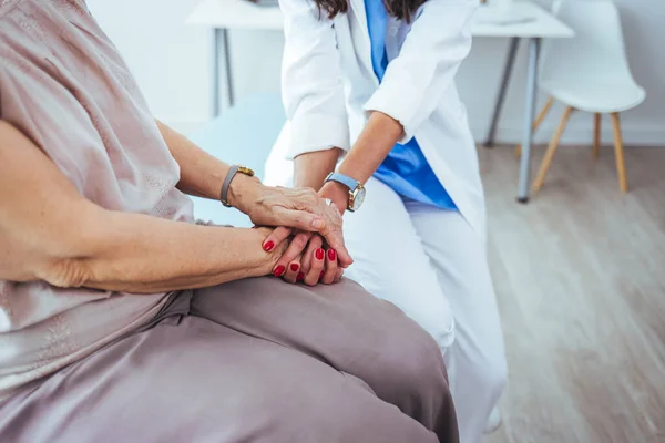stock image young female doctor holding hand of her senior patient in clinic