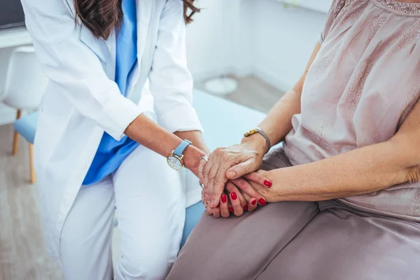 stock image young female doctor holding hand of her senior patient in clinic