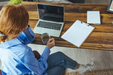 Uzaktan kumanda evden çalışıyor. Dizüstü bilgisayarlı, kahveli, gözlüklü serbest çalışan bir iş yeri.