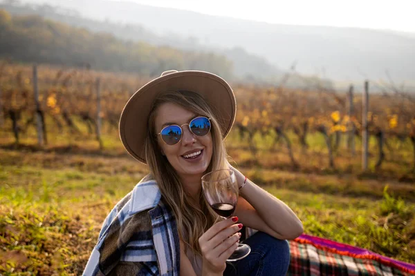 Woman in vineyard in sunset beautiful young woman with hat in vineyards in sunset in summer. Young woman with glass of wine in vineyard on sunny day. Woman tasting wine in vineyard