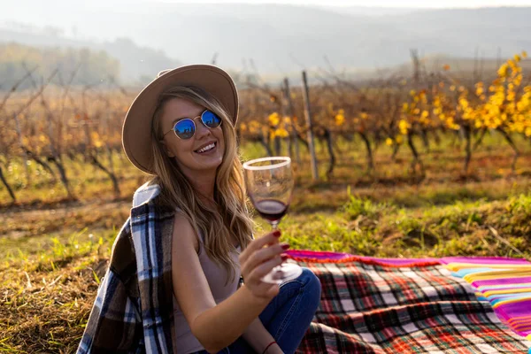 Portrait of a gorgeous woman tasting wine in the vineyards. Outdoors portrait of a beautiful wine tasting tourist woman. Female Winemaker with Glass of White Wine in Vineyard