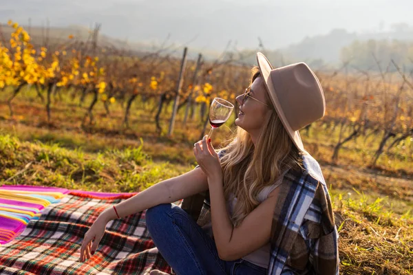 日落时在葡萄园喝红酒的微笑女子的画像 一个夏日的下午 一个女人在葡萄园里品酒 她的嘴上沾着淡淡的酒味 所以她的酒味道很好 — 图库照片