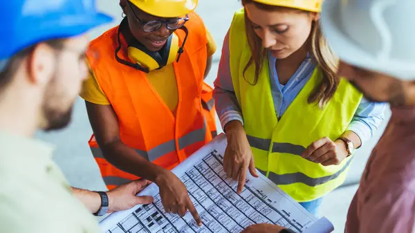 group of people with blueprint at construction site.