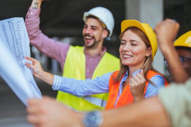 İnşaat alanının planlarını elinde tutan bir grup başarılı mühendis