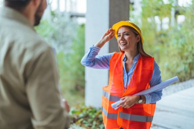 İnşaat alanında duran kasklı ve çelik yelekli genç bayan mühendis. 
