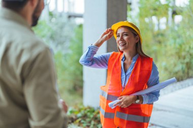İnşaat alanında duran kasklı ve çelik yelekli genç bayan mühendis. 