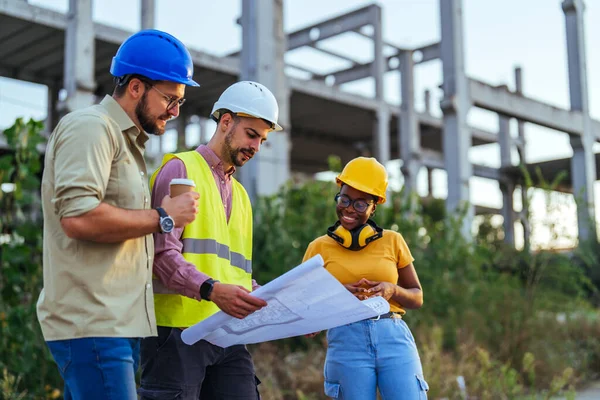 Group of engineers looking at a blueprint at construction site