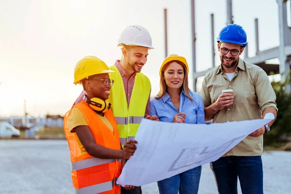 Group of engineers looking at a blueprint at construction site