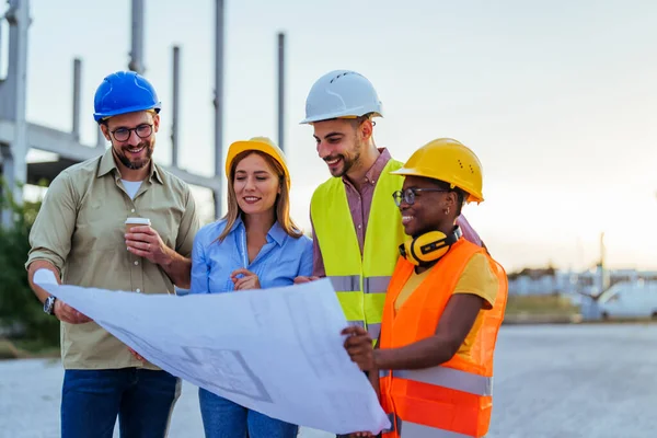 Group of engineers looking at a blueprint at construction site