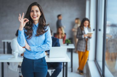 Kafkasyalı genç iş kadını arka planda bulanık ofiste iş arkadaşlarıyla 