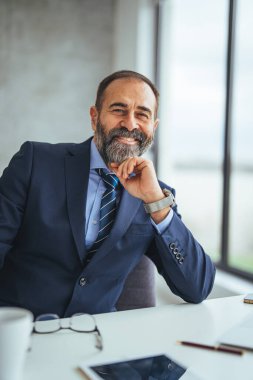 Ofiste resmi takım elbise giymiş gülümseyen beyaz iş adamının portresi.