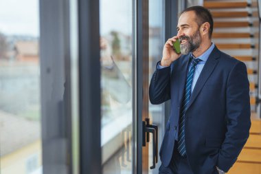 Ofiste akıllı telefondan konuşan Kafkasyalı iş kadını