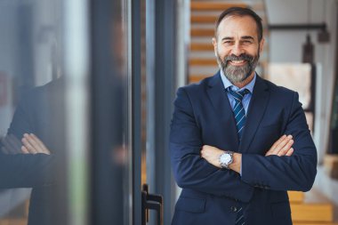Ofiste kollarını kavuşturmuş gülümseyen beyaz iş adamının portresi.