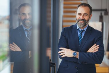 Ofiste kollarını kavuşturmuş gülümseyen beyaz iş adamının portresi.