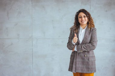 Çekici genç bir iş kadınının gün boyunca kolları bağlı bir şekilde ofisinde dikilirken çekilmiş portresi. Modern bir ofiste duran bir iş kadınının portresi.