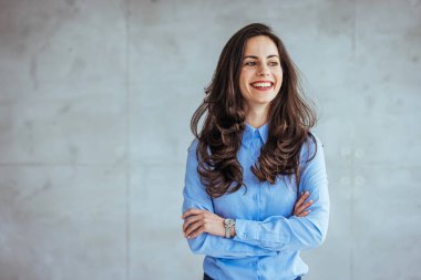 Salonda dikilen ve gülümseyerek kameraya bakan mutlu bir iş kadını. Beyaz arka planda stüdyo fotoğrafı. İspanyol modeli. Modern bir ofiste çalışan kendinden emin genç bir iş kadınının portresi.