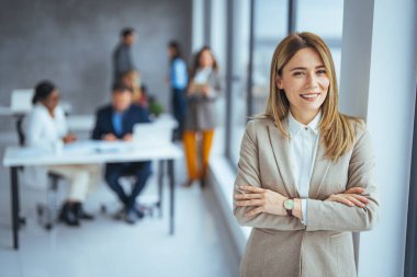 Modern bir ofiste çalışan kendinden emin bir iş kadınının portresi. Çekici genç bir iş kadınının gün boyunca kollarını kavuşturmuş bir portresi.