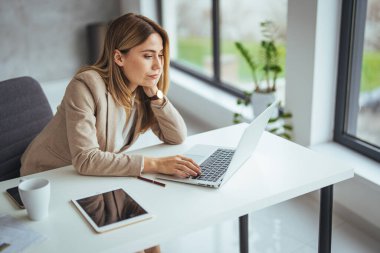 Çalışma masasında bilgisayar kullanırken stresten muzdarip genç bir kadının fotoğrafı. Masasında oturan baş ağrısı olan bir girişimci kadın. Stres ve gerilim başa çıkılamayacak kadar arttı.