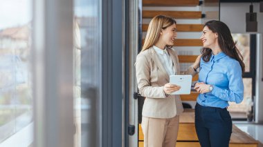Modern bir ofiste dijital tablet üzerinde çalışan meslektaşlarımızın görüntüsü. Ofisteki dijital tablette birlikte çalışan iki iş kadınının fotoğrafı.. 