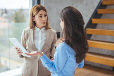 Modern bir ofiste dijital tablet üzerinde çalışan meslektaşlarımızın görüntüsü. Ofisteki dijital tablette birlikte çalışan iki iş kadınının fotoğrafı.. 