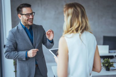 Yeni projeyi tartışan iki meslektaşın görüntüsü. İş adamı ve iş kadını dijital tablet kullanıp iş stratejisini tartışıyor. Ofiste birlikte çalışan kendine güvenen iş adamları..