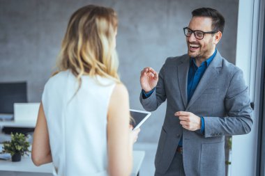 Şirket çalışanları yeni projeyi tartışıyor ve iş yerinde fikirlerini paylaşıyorlar. İşteki bir iş toplantısında iki iş arkadaşının dijital tablet kullanması. 