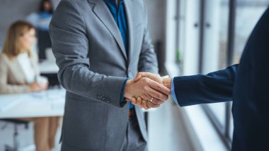 Ofiste el sıkışan iki iş adamını vurdular. İki gülümseyen iş adamı ofiste dururken el sıkışıyor. İş adamları el sıkışıyor, toplantıyı bitiriyor.