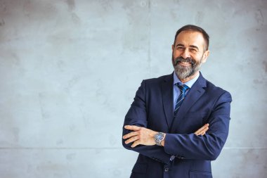Modern bir ofiste çalışan kendinden emin bir iş adamının portresi. Kameraya bakan olgun bir adamın portresi. Kendine güveni tam. Ofiste çalışıyor. Modern ofiste olgun bir iş adamının portresi.