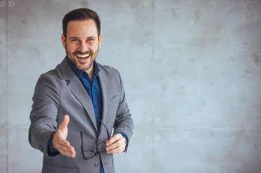 Resmi kıyafet giymiş başarılı bir genç adamın resmi olarak gülümseyen portresini kapatıyoruz. İnsan kaynakları çalışanı elini kameraya uzatıyor. Size şirkette iş teklif etmekten memnuniyet duyuyor.