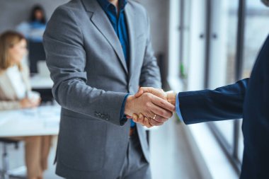 Ofisteki iş adamları ayakta ve el sıkışıyorlar, yakın plan. İş iletişimi kavramı. El sıkışma ve pazarlama. Gülümseyen iki işadamı el sıkışıyor. 