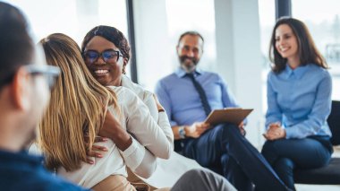 Grup terapi oturumunda kucaklaşan Afrikalı Amerikalı ve Asyalı kadınlar, empati konsepti, psikolojik destek, çeşitli arkadaşlar sorunu birlikte aşın, bağımlılık tedavisi veya takım oluşturma