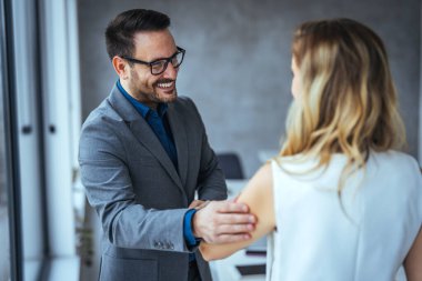 Başarılı bir toplantıdan sonra iş adamları el sıkışıyor. İş adamı ve iş kadını ofiste tokalaşıyor. İş adamı, başarılı takım çalışmasını kutlayan kadın ortağıyla el sıkışıyor..