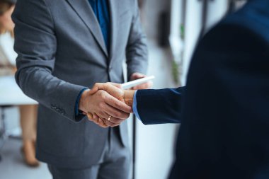 İyi bir anlaşma. İş yerinde otururken el sıkışan iki iş adamının yakın çekimi. İşçilik, çalışma, başarı konsepti. Yöneticinin yeni çalışanıyla el sıkışma portresi.