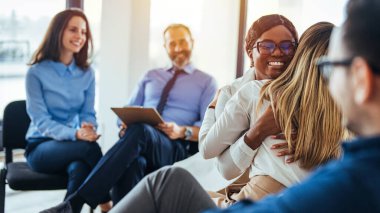 Grup terapi oturumunda kucaklaşan Afrikalı Amerikalı ve Asyalı kadınlar, empati konsepti, psikolojik destek, çeşitli arkadaşlar sorunu birlikte aşın, bağımlılık tedavisi veya takım oluşturma