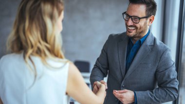Anlaşmayı mühürlüyorum! Karşılama ortakları toplantılarını bitirdikten ya da hedefler belirledikten ve ofiste başarıya giden yolu planladıktan sonra el sıkışan iki iş adamı. Neşeli genç müdürün yeni çalışanıyla tokalaşması portresi.