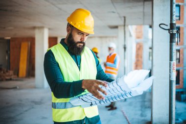 Şantiyede çalışan, arka planda bulanık meslektaşları olan, kafkasyalı bir mühendis.